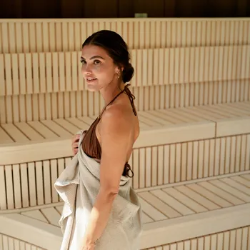 Hotel mit Sauna Frau im Badeanzug mit Handtuch steht in moderner Holzsauna
